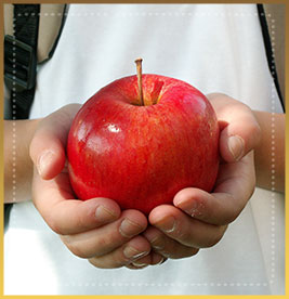 Student holds an apple in their hand